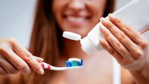 Closeup of woman putting toothpaste on toothbrush
