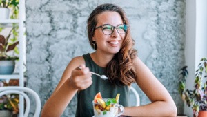 Woman smiling while eating well-balanced breakfast