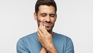 Bearded man rubbing his jaw in pain