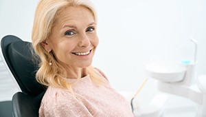 Woman in pink shirt sitting in dental chair smiling