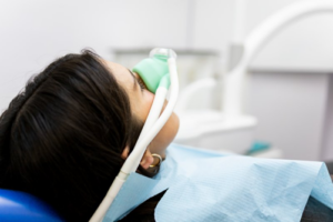 Woman relaxing in patient’s chair with nitrous oxide sedation mask