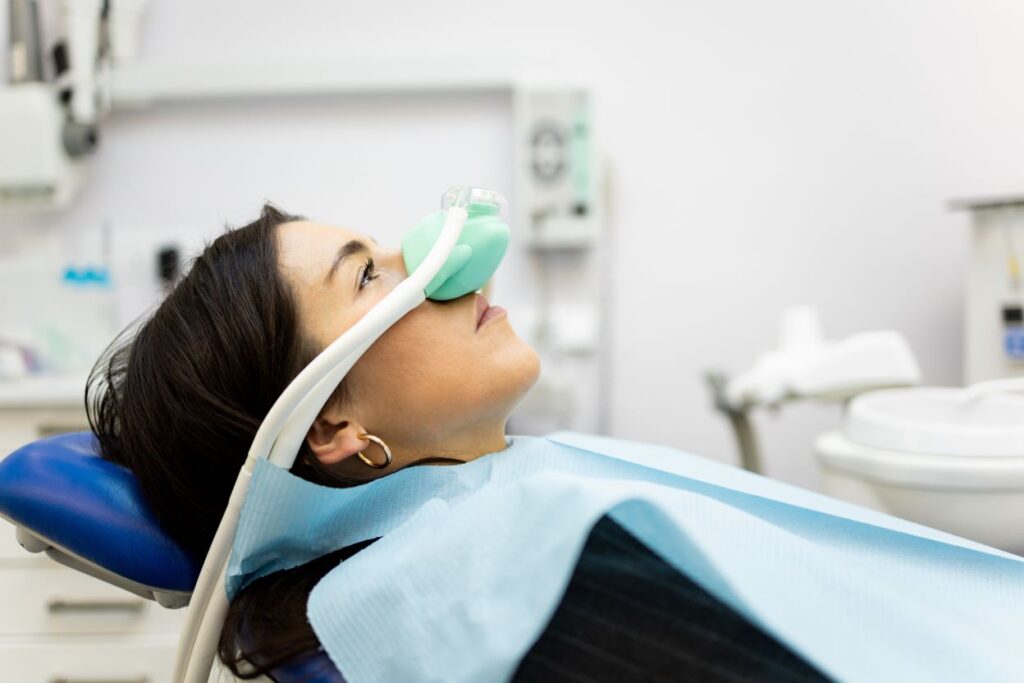 A woman in a dental chair wearing a nose mask for nitrous oxide.